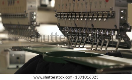 Close up picture workspace of embroidery machine show embroider line design theme. And three thread s white black and red color.