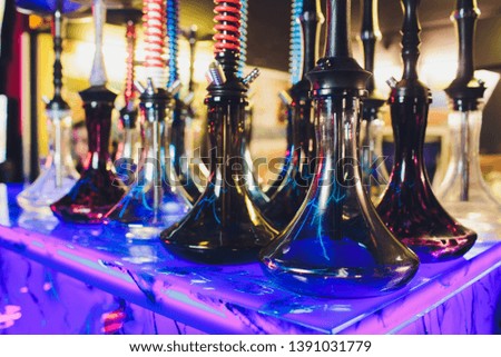 empty glass hookahs under the light of neon against the background of the restaurant. beautiful frame to insert text.