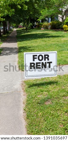 FOR RENT sign posted in lawn advertising home for rent.
