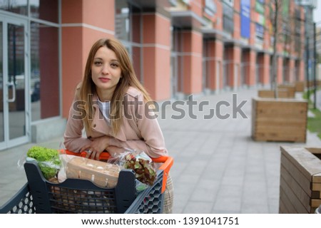 Beautiful girl in the trolley near the supermarket. Outdoor