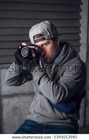 A man is a photographer with camera. Funny Face. Dark gray background. The photographer shoots at the camera. Picture of the camera. Profession