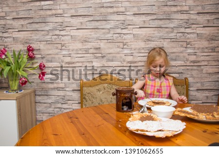 a five-year-old girl smears Belgian waffles at a table with chocolate
