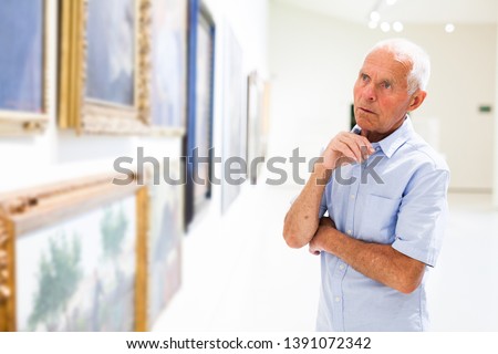 Portrait of elderly man examining painting  modern art gallery
