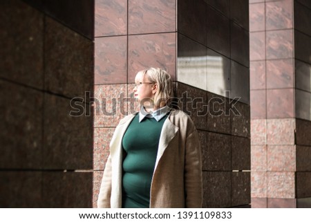 Portrait of a thick blonde woman in a trench coat of beige and a green dress. Trends 2019. Fashion photography on the street