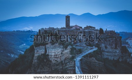 The village of Civita di Bagnoregio, one of the most beautiful in Italy, with its steep walls, photographed after sunset with the first lights of the city coming on sunset