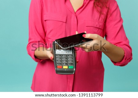 Cropped image woman hold mobile phone wireless modern bank payment terminal to process acquire credit card payments isolated on blue turquoise background. People lifestyle concept. Mock up copy space