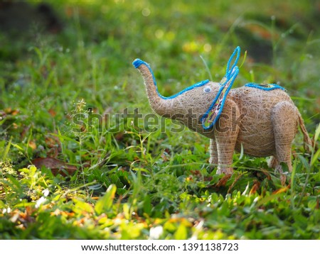 A traditional homemade elephant (gajah) doll close up from fragrant root (akar wangi) above the grass. Using as a background or wallpaper.
