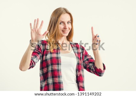 Beautiful young woman shows six fingers while standing on a light background. Number 6.