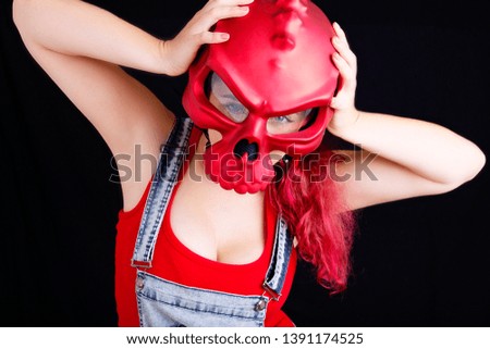 A young woman in denim overalls and red biking helmet on black background