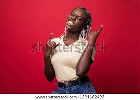 Beautiful young african american woman shouting with crazy expression doing rock symbol with hands up over red isolated background.