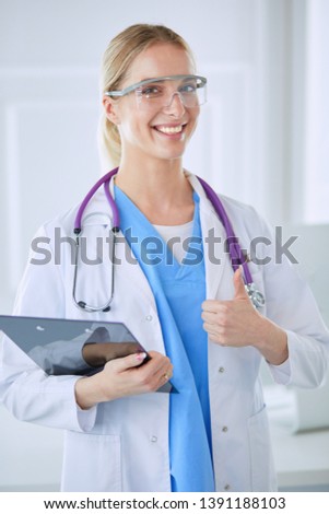 Smiling doctor woman in blue uniform with stethoscope showing okay sign hand gesture isolated on white background