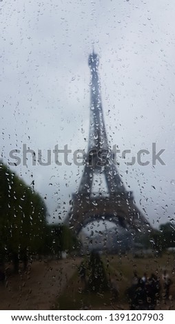 Photo of the Eiffel tower seen trough a wet window. 