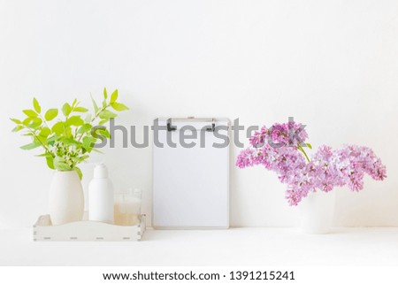 Home interior with decor elements. Mockup clipboard, branches of lilac in a vase, interior decoration