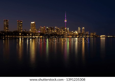 Urban landscape - Toronto City skyline at night, clear dark sky, colorful light reflection in the calm water surface of lake Ontario. Long exposure. Big city nightlife concept.
