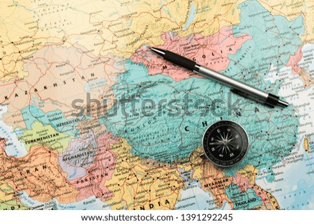 magnetic compass and a pen on map.
