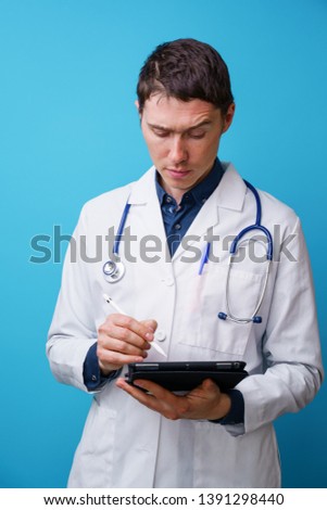 Portrait of doctor with stethoscope and tablet computer in hand on blue background
