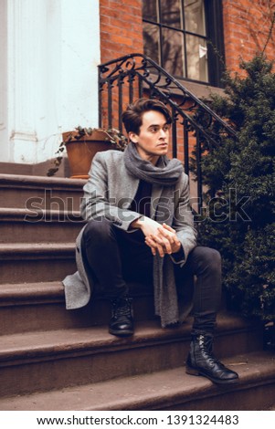 Handsome young man wearing winter clothes sitting on the stairs. Street photo concept.