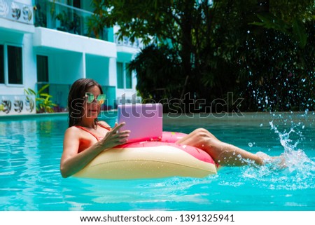 girl in the inflatable circle in the pool with a laptop, the concept of freelancing and recreation