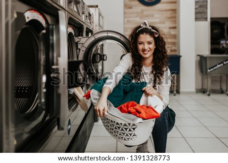 Beautiful female employee working at laundromat shop. Royalty-Free Stock Photo #1391328773