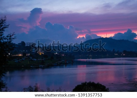 lake in the mountains after sunset. twilight, colorful clouds in the sky. mountains are blue, violet and blue reflections on the water and in the sky. the road along the lake