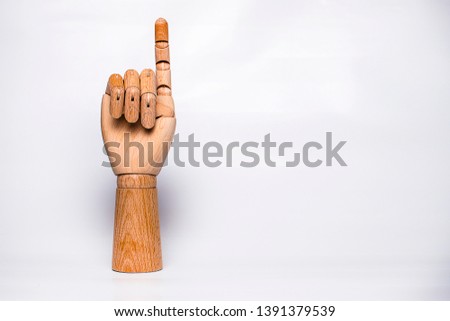 Orthopedic wooden hand on white background, raising index finger.