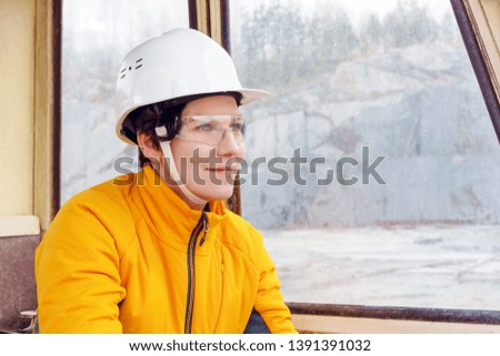 woman in a hard hat and goggles in the cab of heavy construction equipment