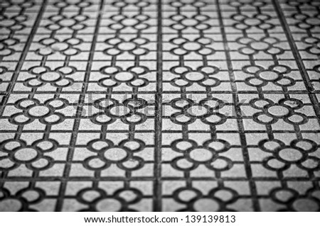 Black and white square tile with geometric pattern and simple flower on each one. Sidewalk paved with tile. Street decoration and design. Abstract backgrounds and wallpapers.