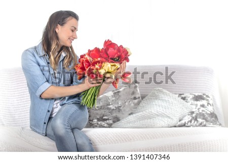 A young girl with a large bouquet of tulips sitting on the couch in the living room .
