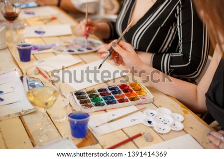 Young women attending aquarelle painting masterclass for adults at an art party in a restaurant.