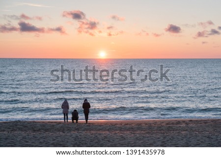 Very beautiful sunset on the Baltic Sea. People walk by the sea.
The sea is calm.