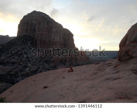 Image of sun rising from Bell Rock, Sedona, Arizona. A small rock stack sits in view on Bell Rock.        