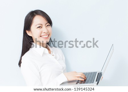 Young business woman using laptop computer against pale blue background