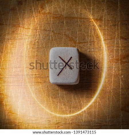 Nauthiz. Handmade scandinavian wooden runes on a wooden vintage background in a circle of light. Concept of fortune telling and prediction of the future.