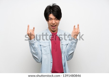 Asian man on isolated white background making rock gesture