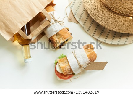 paper bag with sandwiches and bottle of juice at summer day