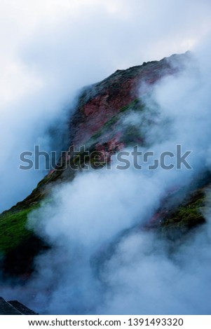 Steam rises from Icelandic hot springs with sulphur turning rock a green and red colour. 