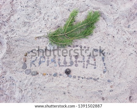 An inscription of small stones meaning "Krishna" is laid out on the sandy shore.
