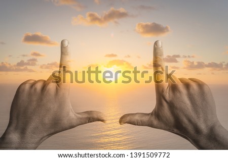 Persons hands making a frame sign over sunset sky, double exposure