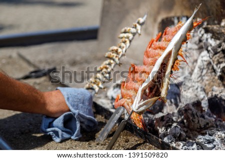 skewers of sardine, sea bass and prawn cooked on the coals in front of the beach
