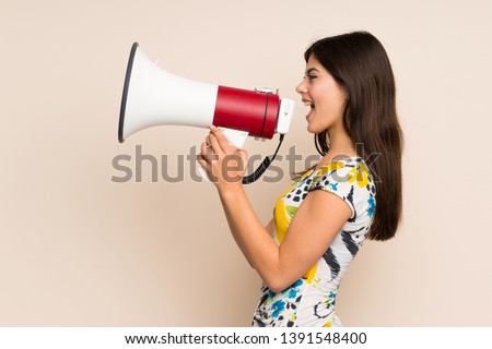 Teenager girl with floral dress shouting through a megaphone