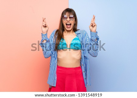 Young woman in bikini with fingers crossing and wishing the best