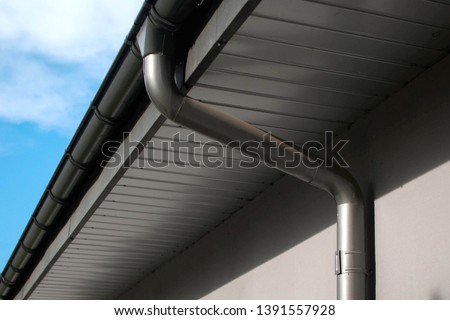 Lateral coated metal Panel, coated Rain Gutter and Rain Water Pipe at a Roof, covered with Metal Shales. Royalty-Free Stock Photo #1391557928