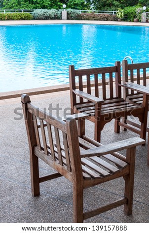 Wooden chair beside the clear pool of  hotel.