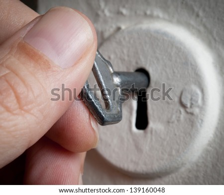 Detail of a  man's hand with key in keyhole.