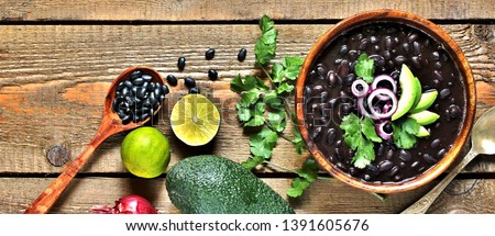 black bean soup or stew. Latin American or Mexican cuisine. stewed black beans served with avocado and red onion and cilantro. place for text. top view. Royalty-Free Stock Photo #1391605676