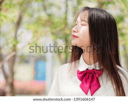 Portrait of a beautiful Chinese girl enjoy sun light and floral fragrance with eyes closed.