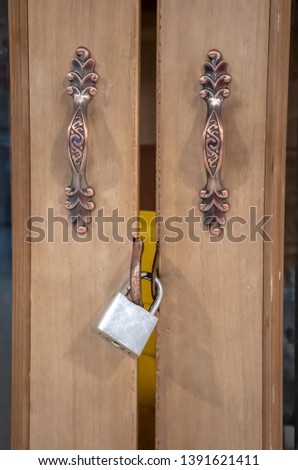 Closeup on gold locked padlock on wooden door.