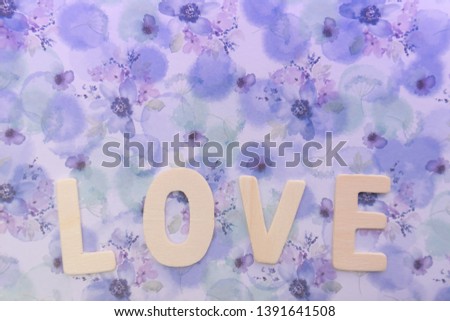Wooden love letter on the violet floral gift wrapped paper as background with copy space or use as wallpaper. Love photo concept.