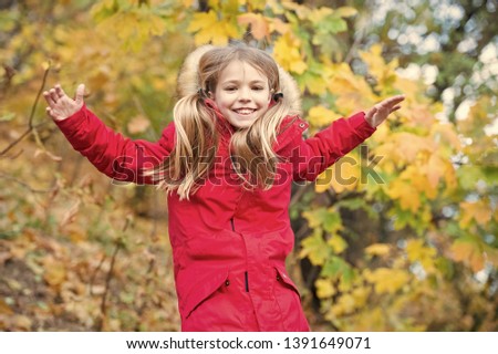 Comfortable and carefree. Child blonde long hair walking in warm jacket outdoor. Girl happy in red coat enjoy fall nature park. Child wear fashionable coat with hood. Fall clothes and fashion concept.