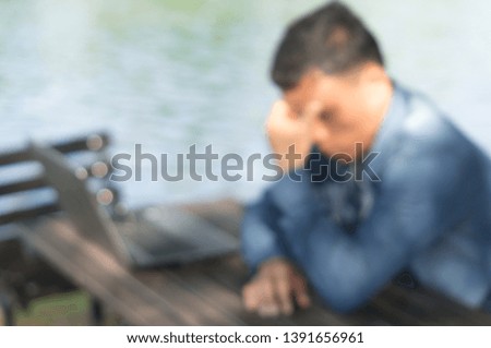 A man are feeling so stressed after sitting to work by using laptop outdoor, blurred picture background